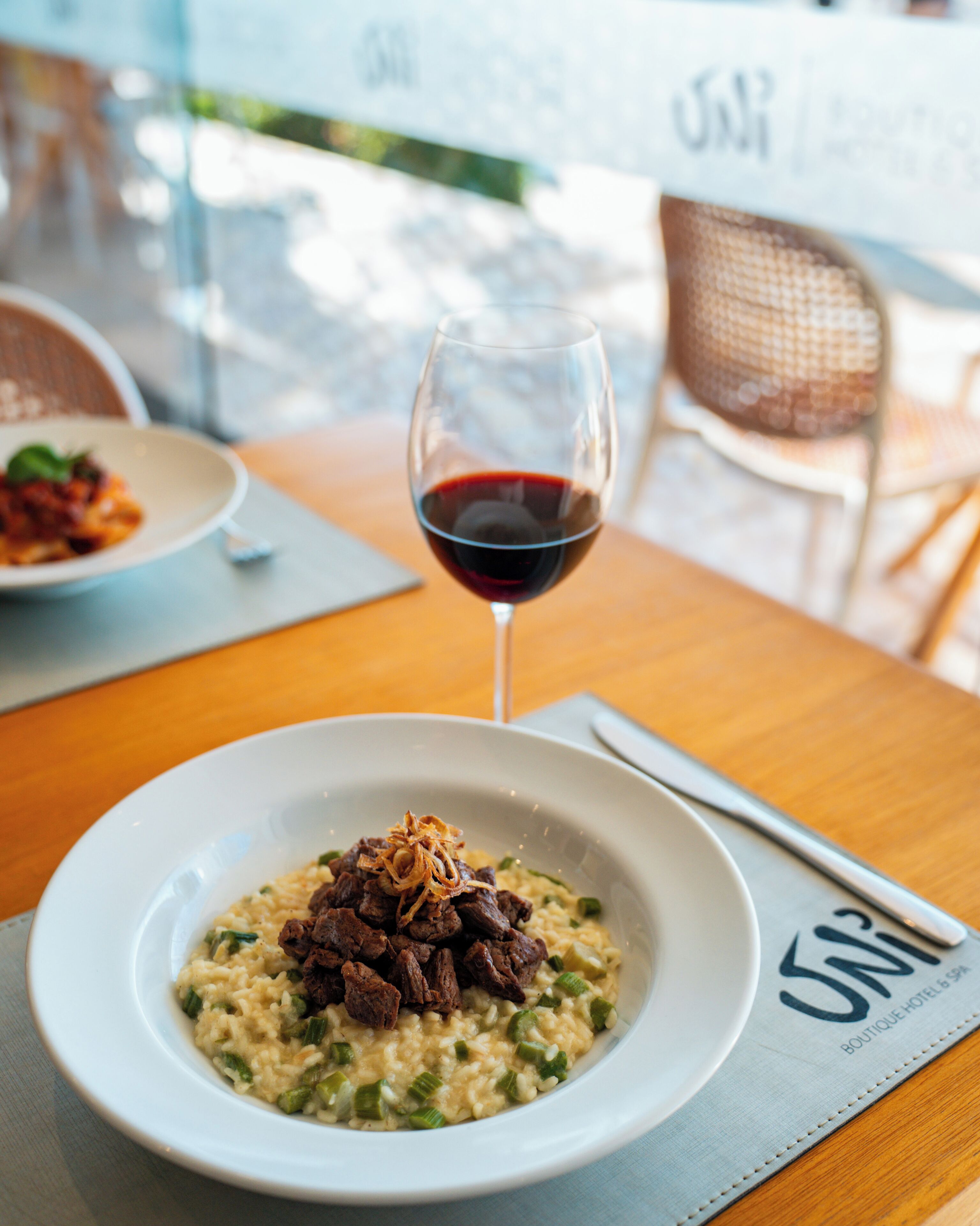 A dining table with a plate of food and a glass of red wine.