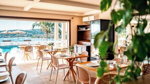Un restaurante con terraza al aire libre que ofrece vistas a una piscina y colinas.