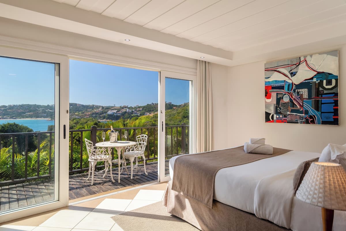 Habitación de hotel con balcón, una cama, un cuadro y vistas del paisaje.