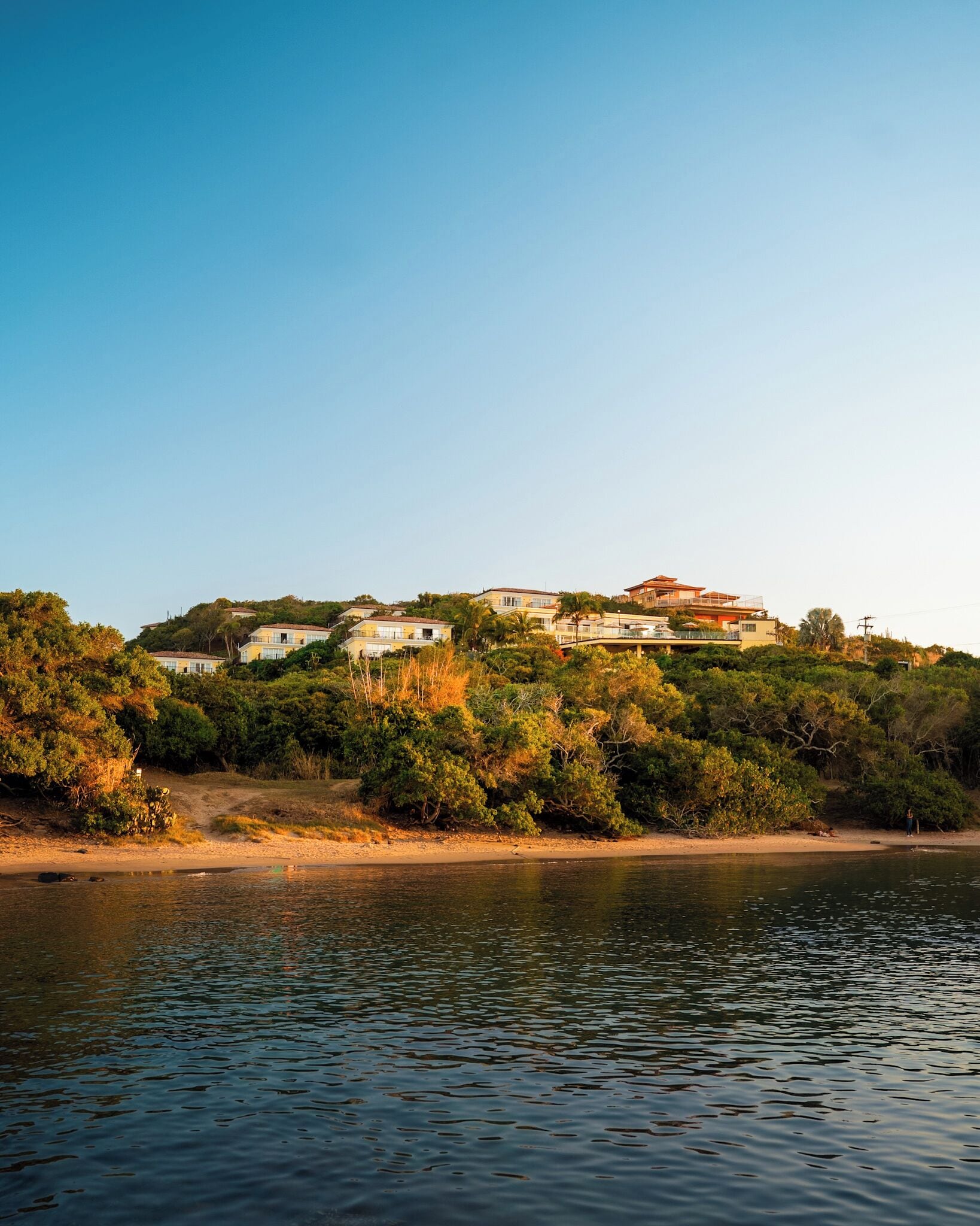 A coastal property with multiple buildings, a beach, and a body of water.