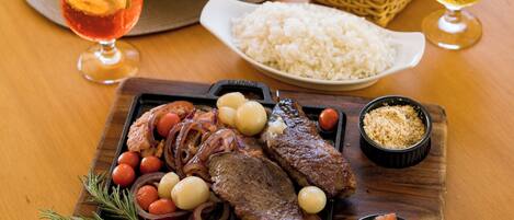 Une table en bois sur laquelle on trouve une variété de plats, notamment un steak, du riz et une salade.