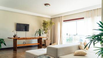 A living room with a sofa, a coffee table, a TV, and a potted plant.