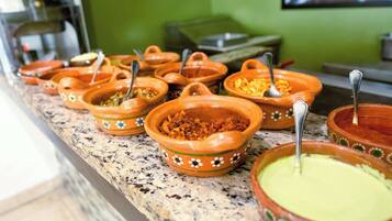 A buffet with various dishes in terracotta bowls, some with spoons.