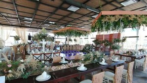 A restaurant with long wooden tables set for dining, surrounded by chairs with patterned covers.