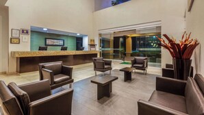 A hotel lobby with leather seating, a reception desk, and framed awards on the wall.