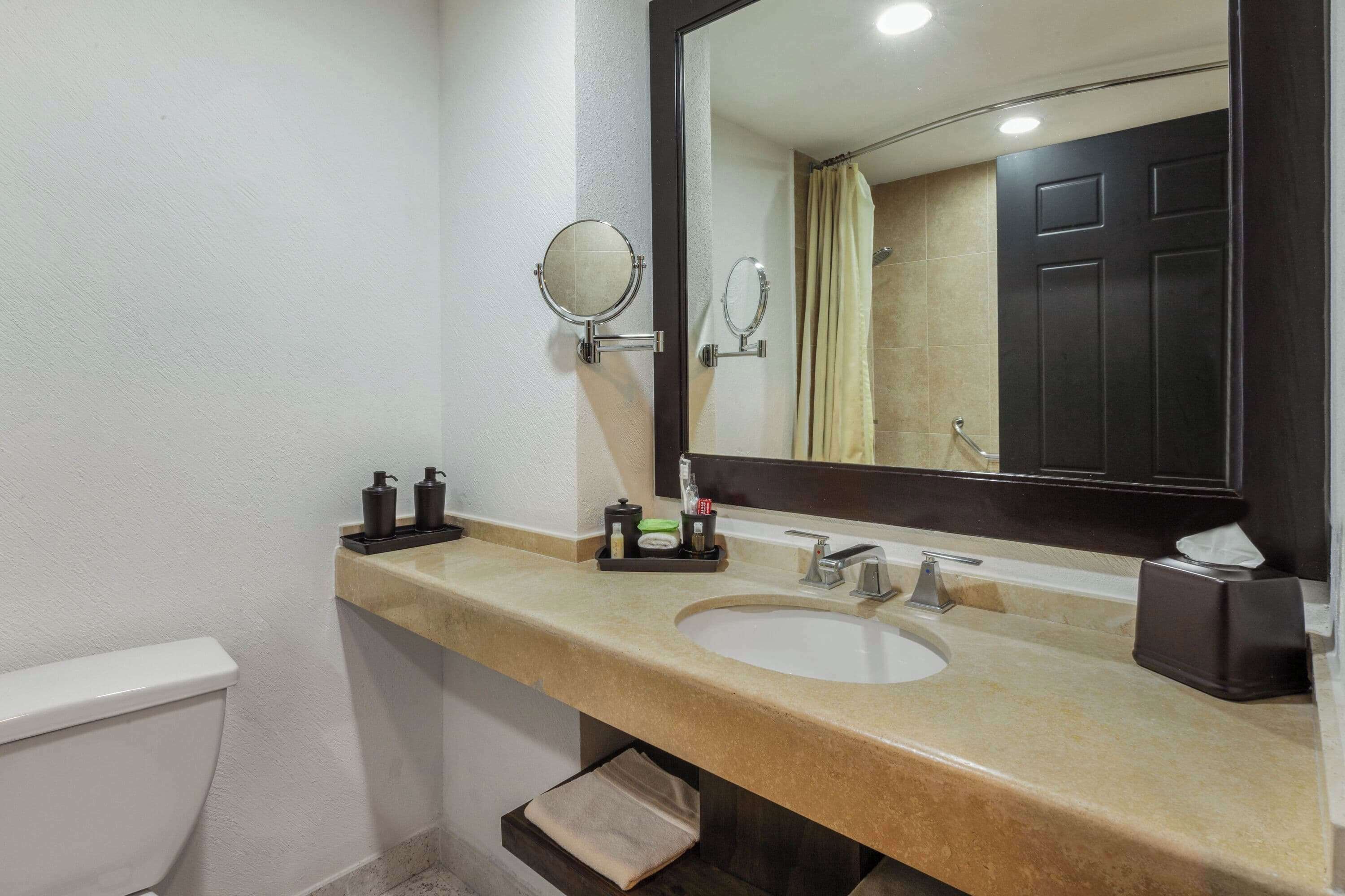 A bathroom with a sink, mirror, and toiletries.