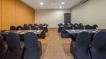 A conference room with rows of tables and chairs, equipped with water bottles and nameplates.