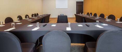 A conference room with a long table, multiple chairs, and a projector screen.