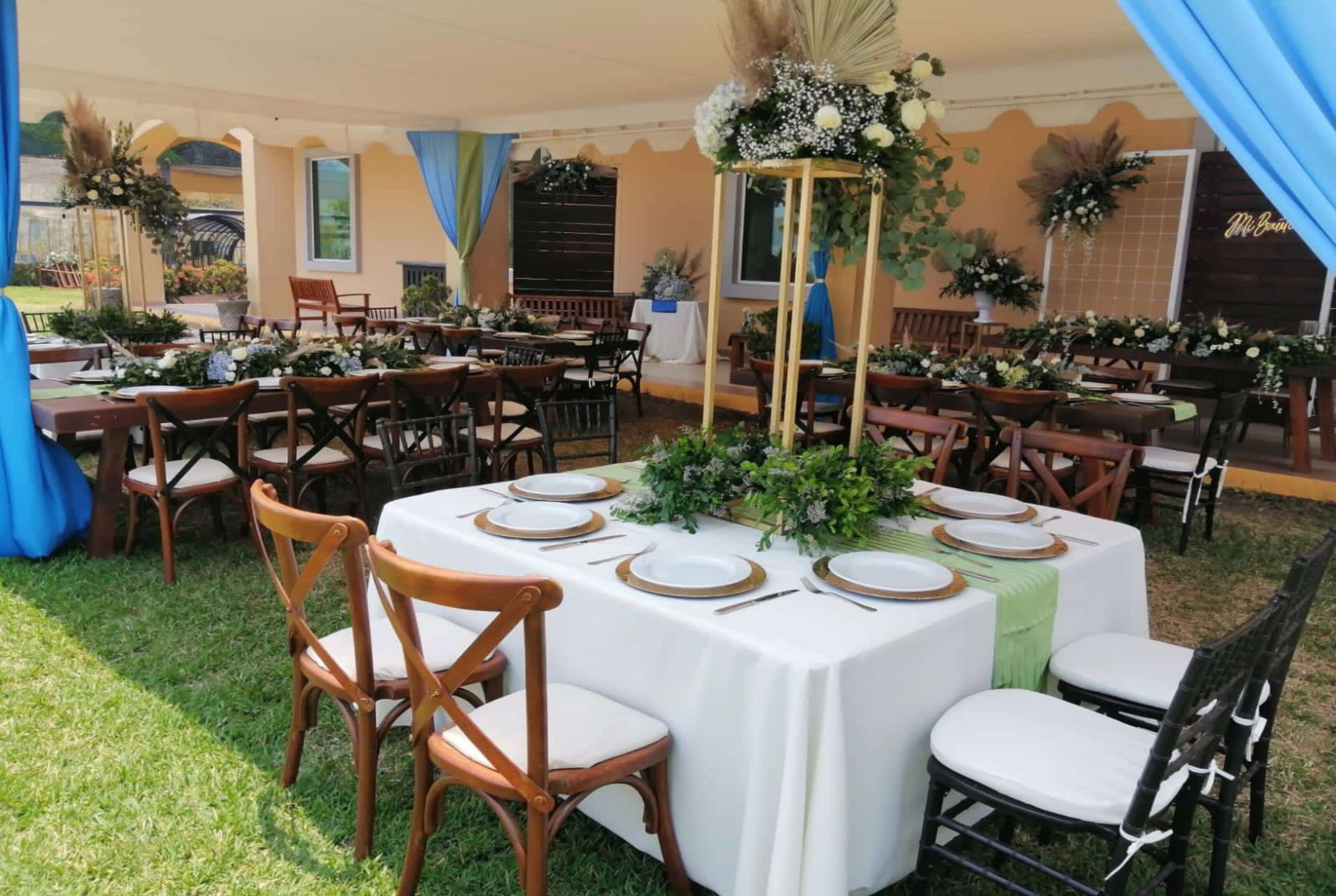 An outdoor dining area with round tables set for a meal, surrounded by chairs.