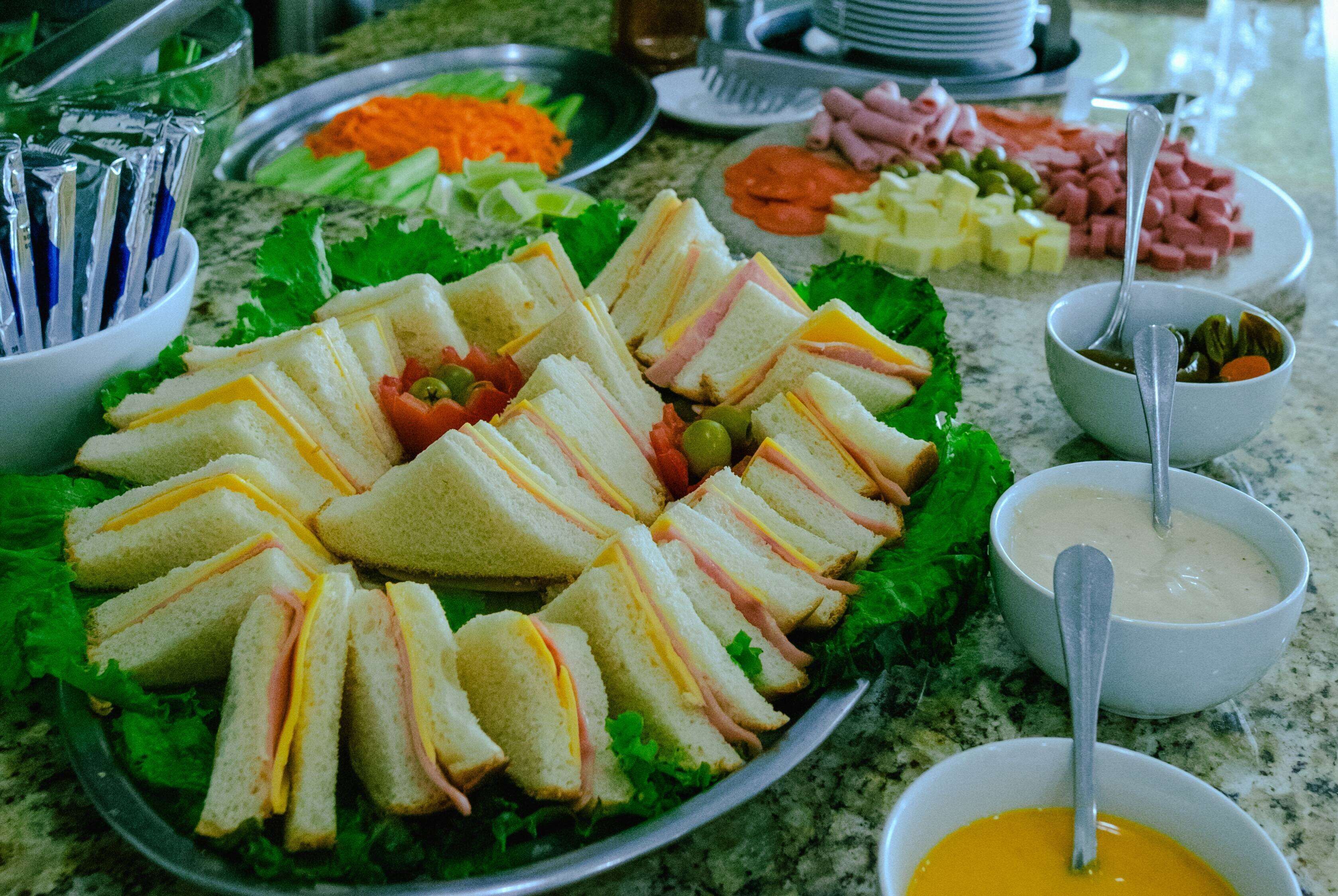 Een buffettafel met diverse gerechten, waaronder belegde broodjes, groenten en dipsauzen.