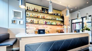 A bar area with shelves of liquor bottles, a counter, and seating. - Best Western Plus Welcome Hotel Frankfurt (Frankfurt)
