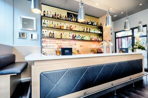 Zona de bar amb estantes plenes de garrafes de licors, una barra i seients.