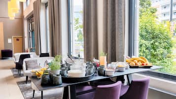 Un comedor moderno con una mesa dispuesta para el desayuno, mostrando diferentes alimentos y utensilios.