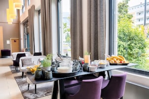 A modern dining area with a table set for breakfast, featuring various food items and utensils.