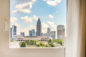 A city skyline viewed through a window with a building in the foreground.