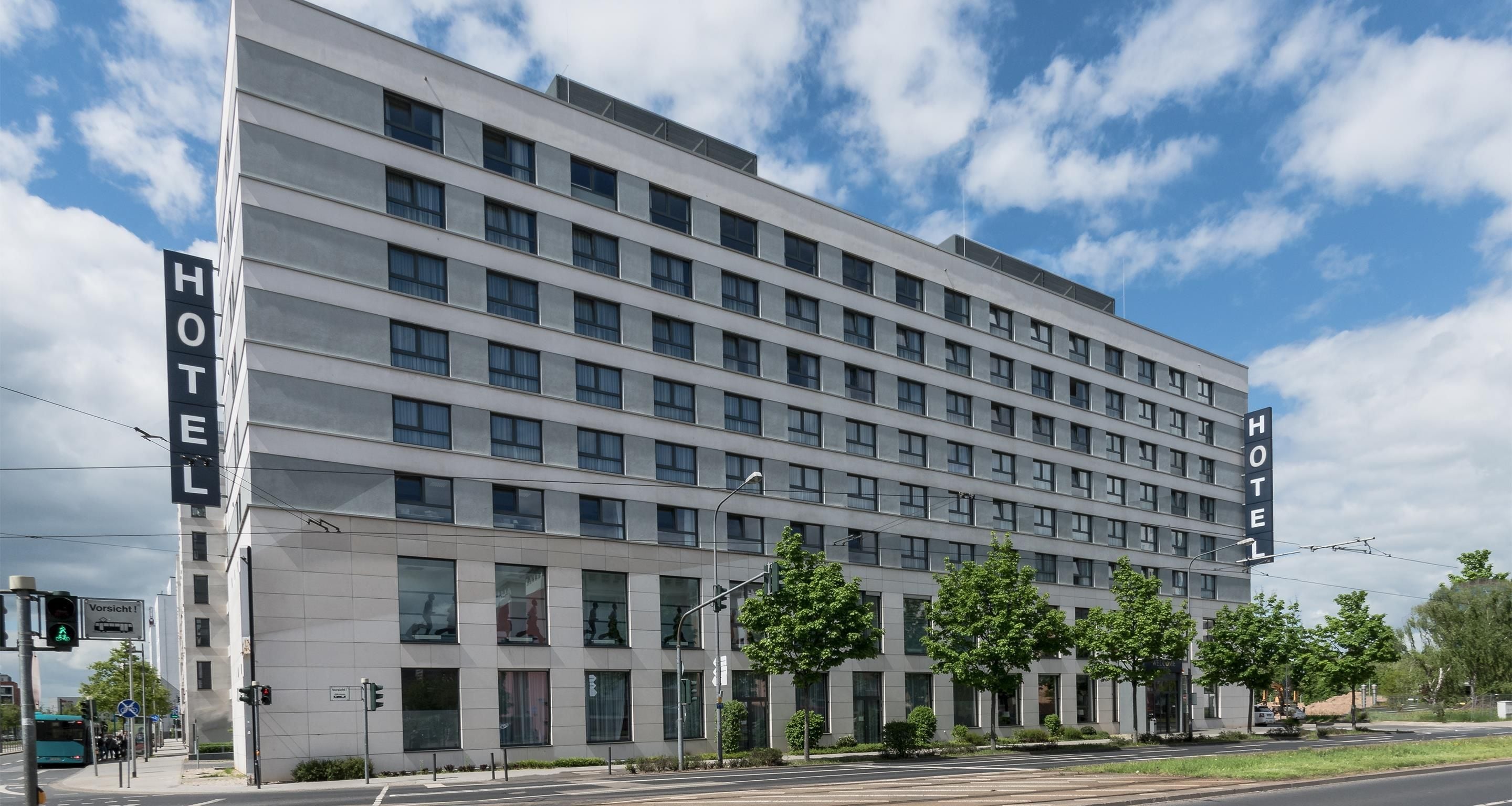 A modern hotel building with multiple floors, large windows, and a prominent 'HOTEL' sign on the facade.