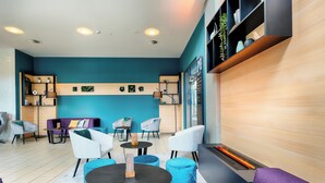 A modern lounge area with a teal wall, wooden shelves, and a fireplace. - Best Western Plus Welcome Hotel Frankfurt (Frankfurt)