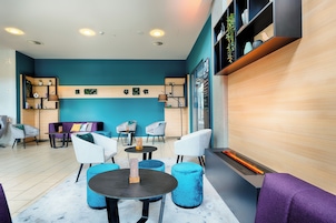 Un'area lounge moderna con una parete verde acqua, scaffali in legno e un camino.