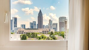 A city skyline viewed through a window with a building in the foreground.