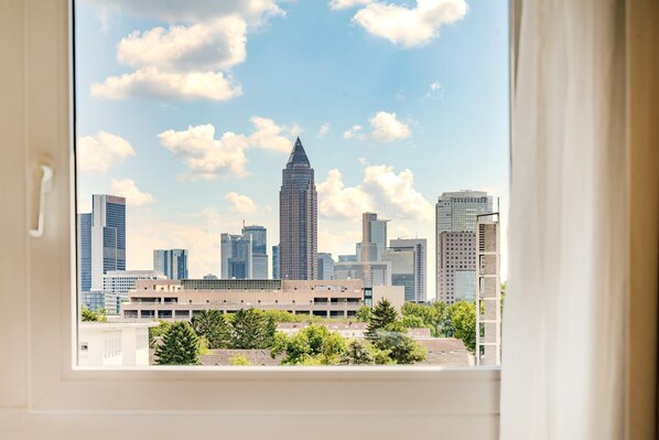 Un horizonte urbano visible a través de una ventana, con un edificio en primer plano.