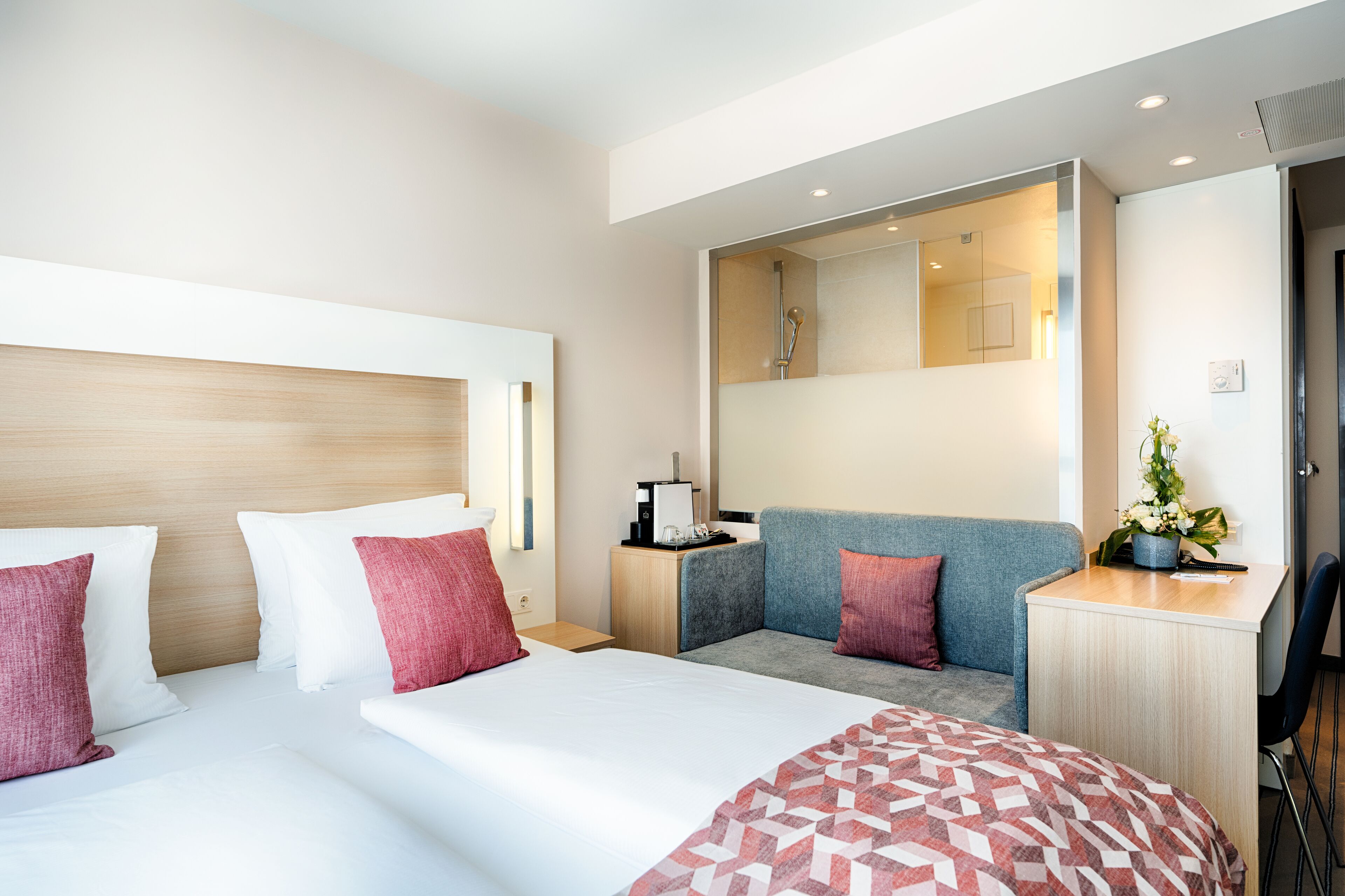 Una habitación de hotel moderna con una cama grande, un sofá, un escritorio y un espejo.