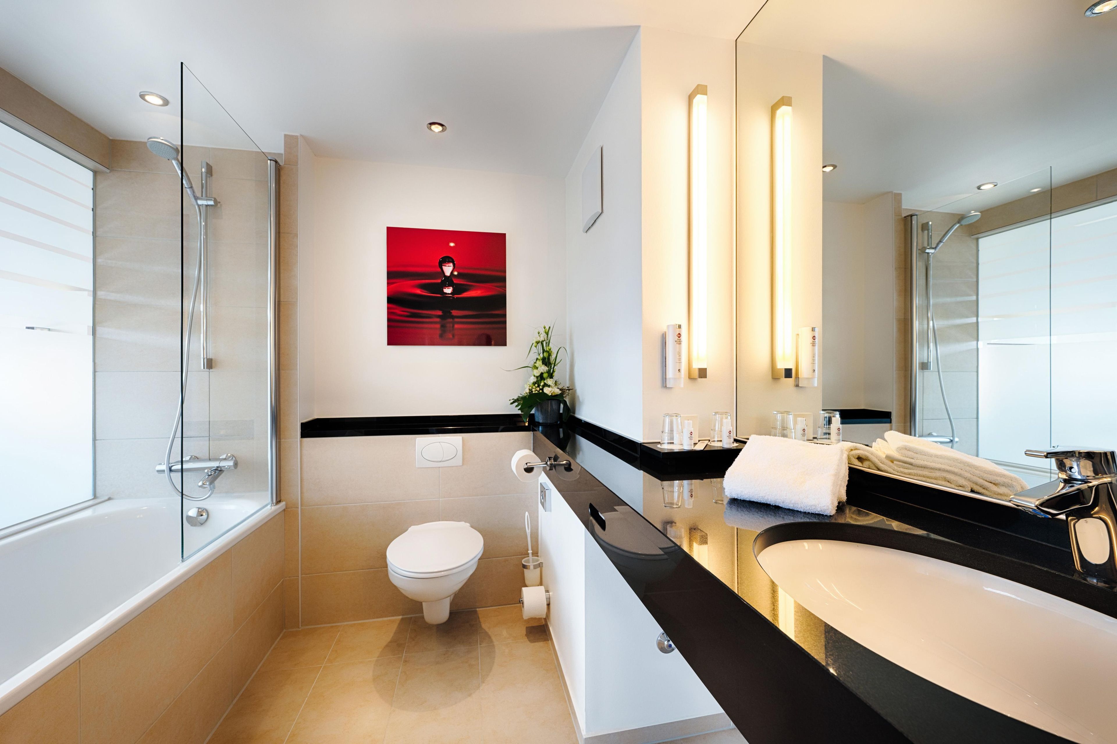 Ein modernes Badezimmer mit Glasdusche, Toilette und Waschtisch mit großem Spiegel.