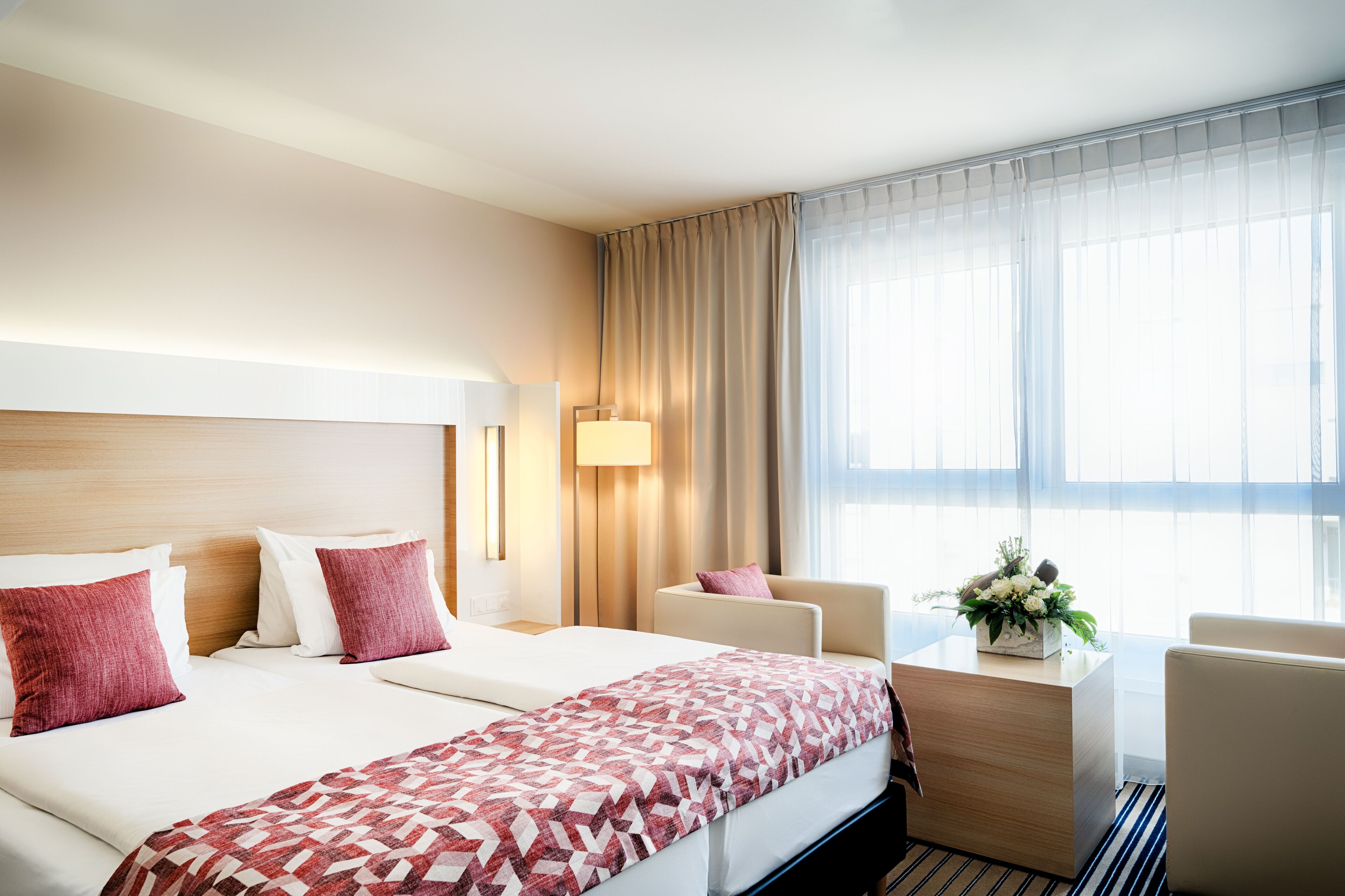 Habitación de hotel con una cama grande, un escritorio, una silla y una ventana con cortinas.