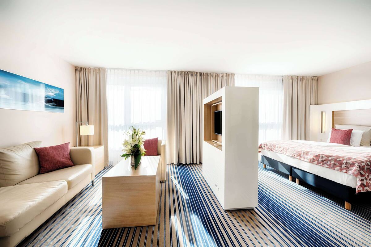 A hotel room with a bed, a sofa, a coffee table, and a TV.