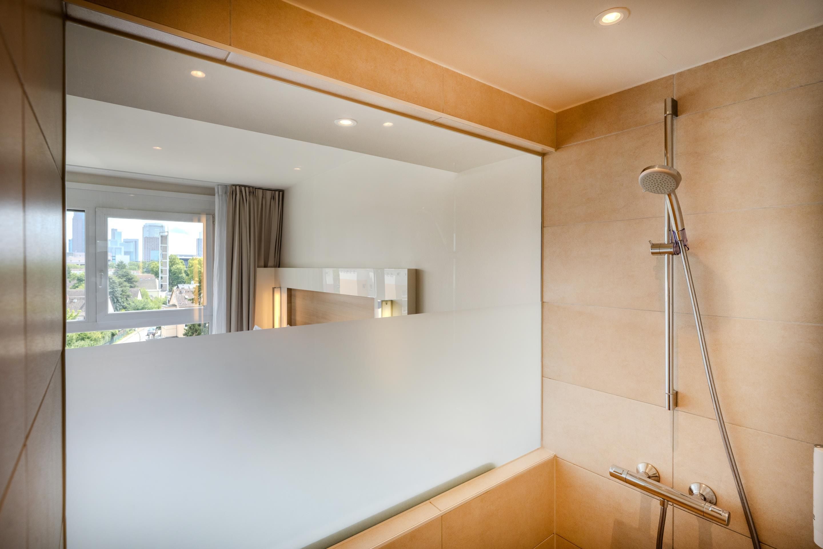 Ein modernes Badezimmer mit Dusche, einem Fenster mit Vorhängen und Blick auf die Stadt.
