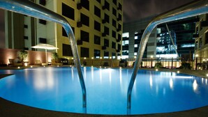 An indoor swimming pool with two metal ladders, surrounded by lounge chairs and a brick wall. - Sterlings Mac Hotel (Bengaluru)