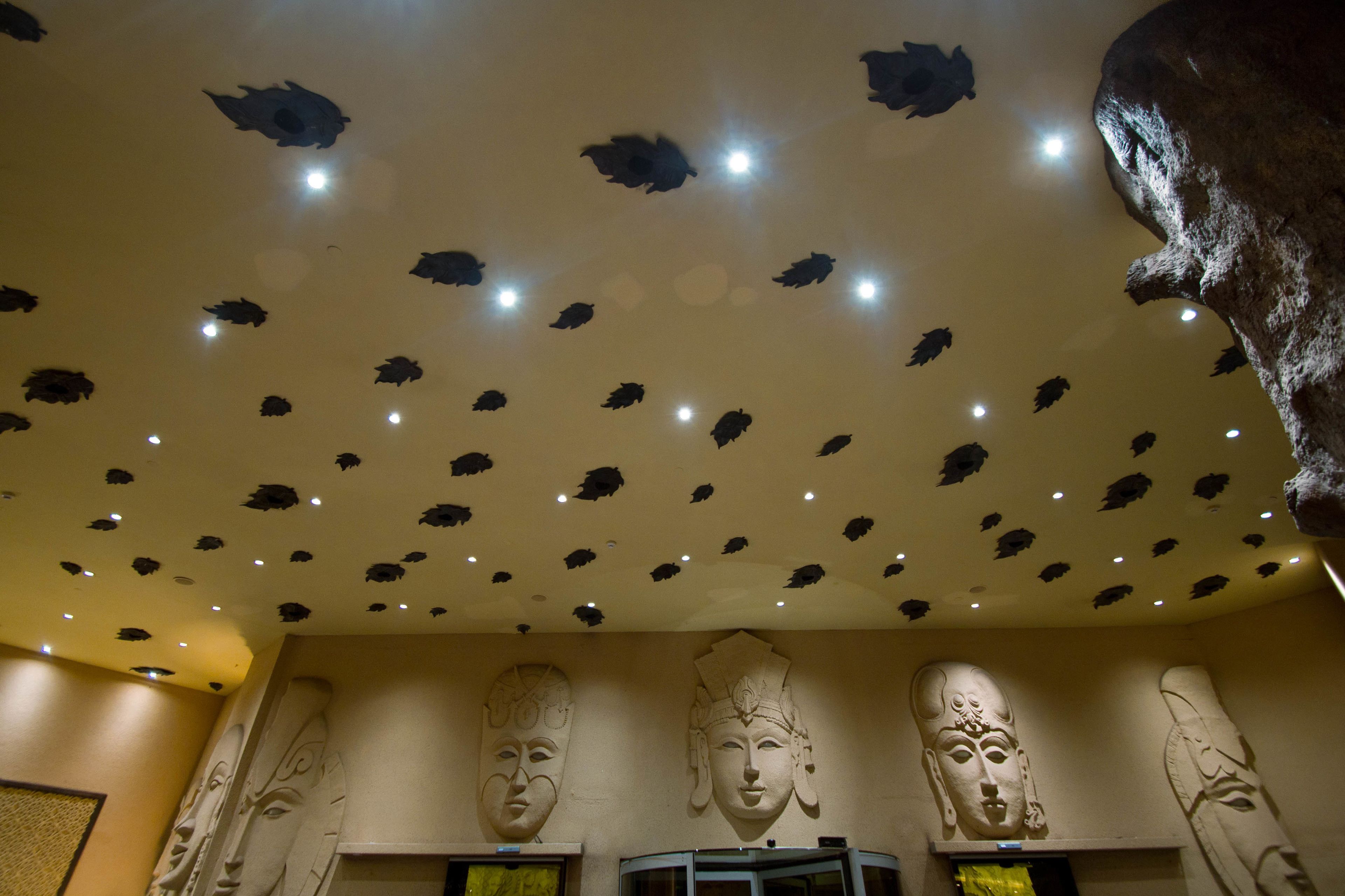 A ceiling with decorative leaf patterns and recessed lighting.