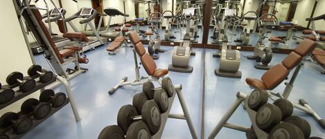 A gym with various exercise equipment, including treadmills, dumbbells, and weight machines.