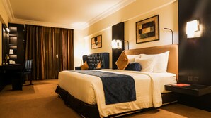 A hotel room with a large bed, a desk, and a chair. - Sterlings Mac Hotel (Bengaluru)
