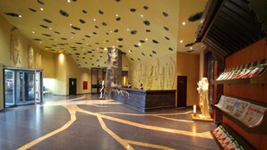 A lobby with a stone column, a reception desk, and a wall with a large mural. - Sterlings Mac Hotel (Bengaluru)
