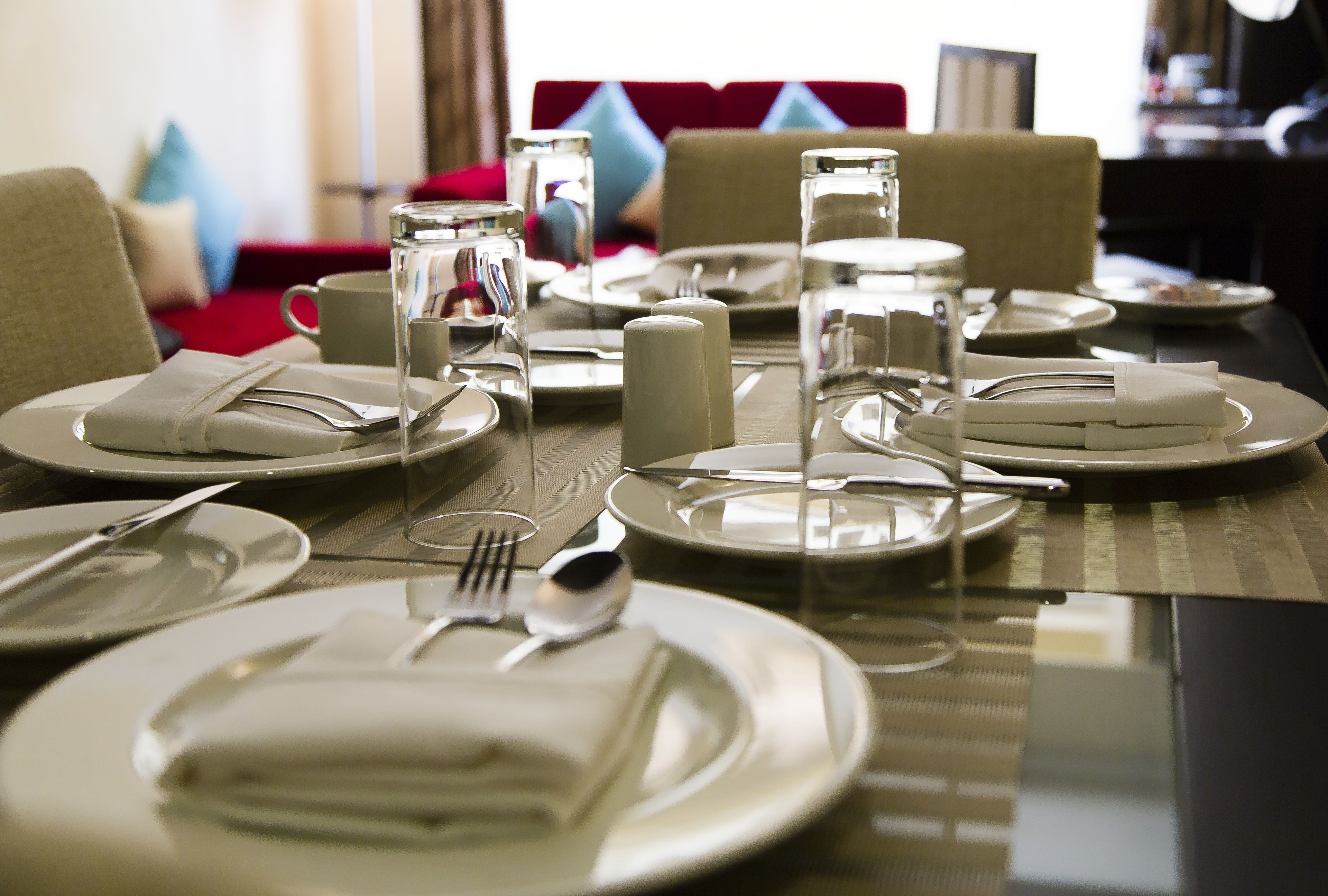 A dining table set with plates, cutlery, glasses, and a pitcher of water.