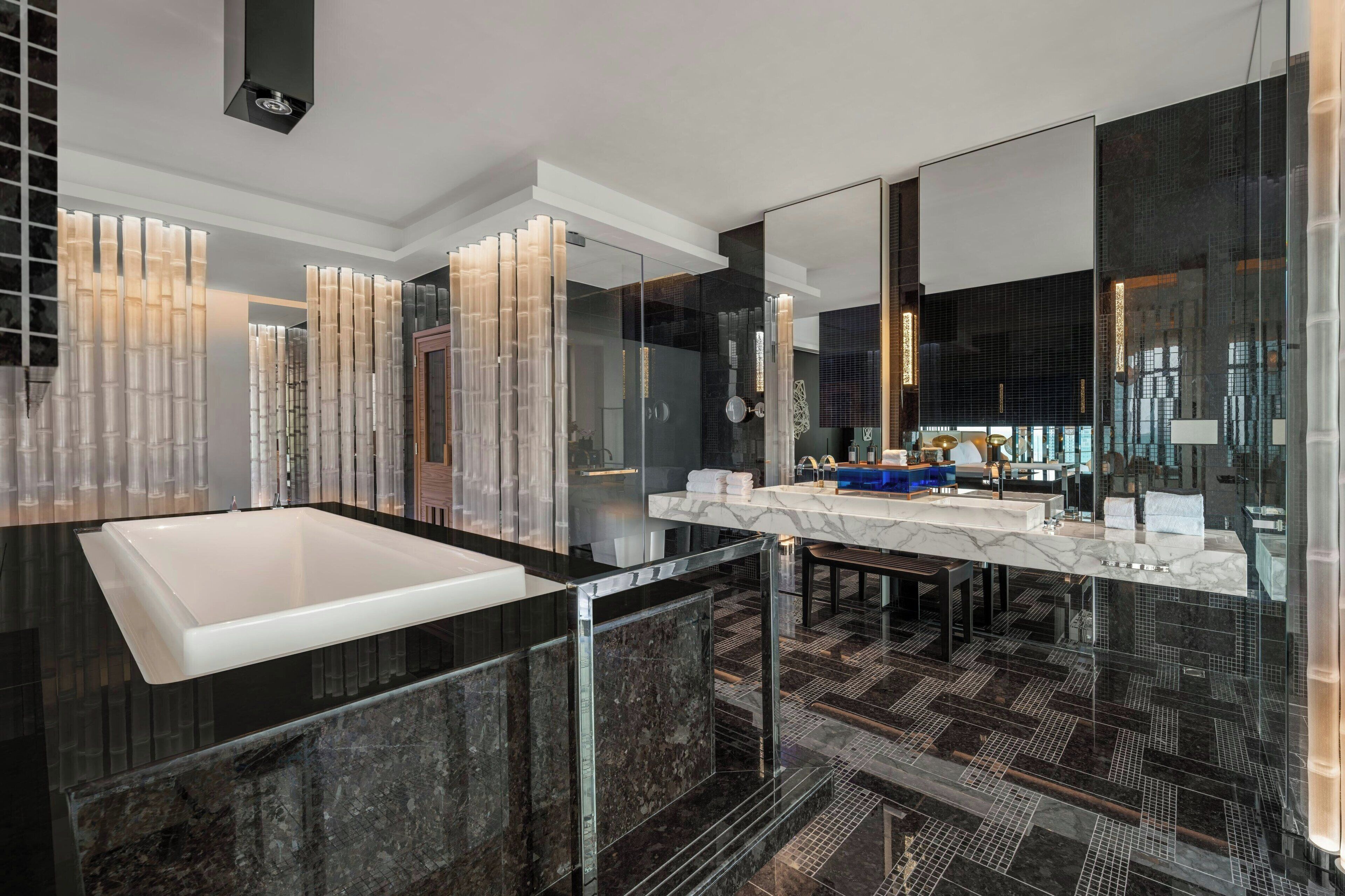 A modern bathroom with a large white bathtub, a double sink vanity, and a large mirror.