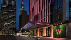 Een modern hotel met een opvallend 'W' logo, een glazen gevel en een goed verlicht entreegebied.