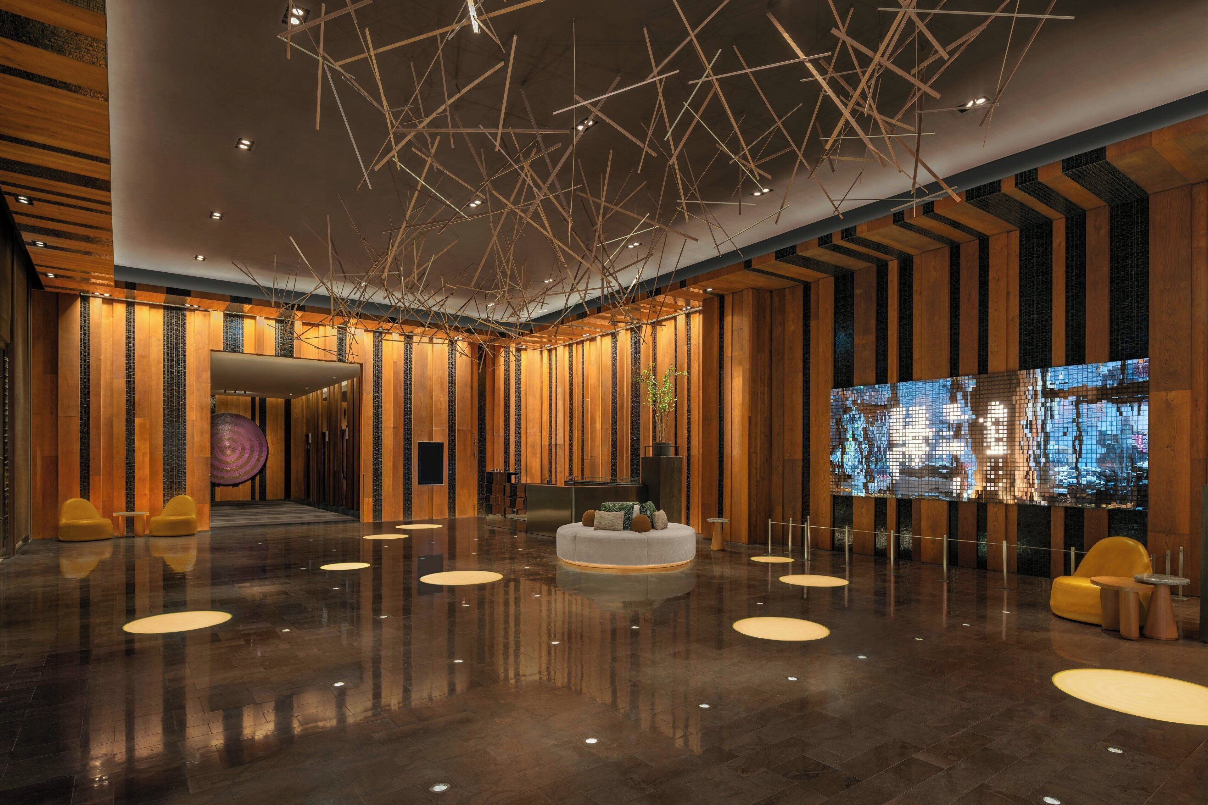A spacious lobby with a polished floor, a reception desk, and a seating area with round tables and chairs.