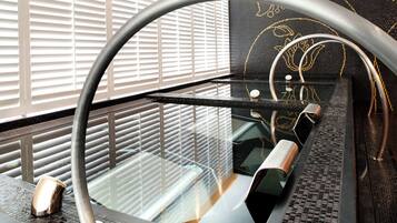 A modern bathroom with a glass-enclosed shower, a curved metal faucet, and a patterned wall.