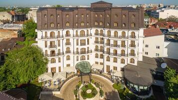 A multi-story hotel with a central courtyard, surrounded by greenery and featuring a traditional architectural style with multiple balconies.
