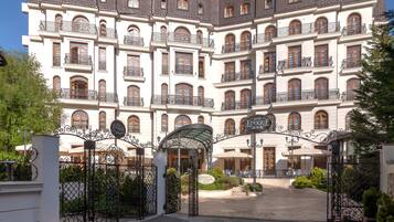 Un hotel grande, de varios pisos, con un estilo arquitectónico clásico europeo, que cuenta con numerosos balcones y una entrada central con puertas ornamentales.