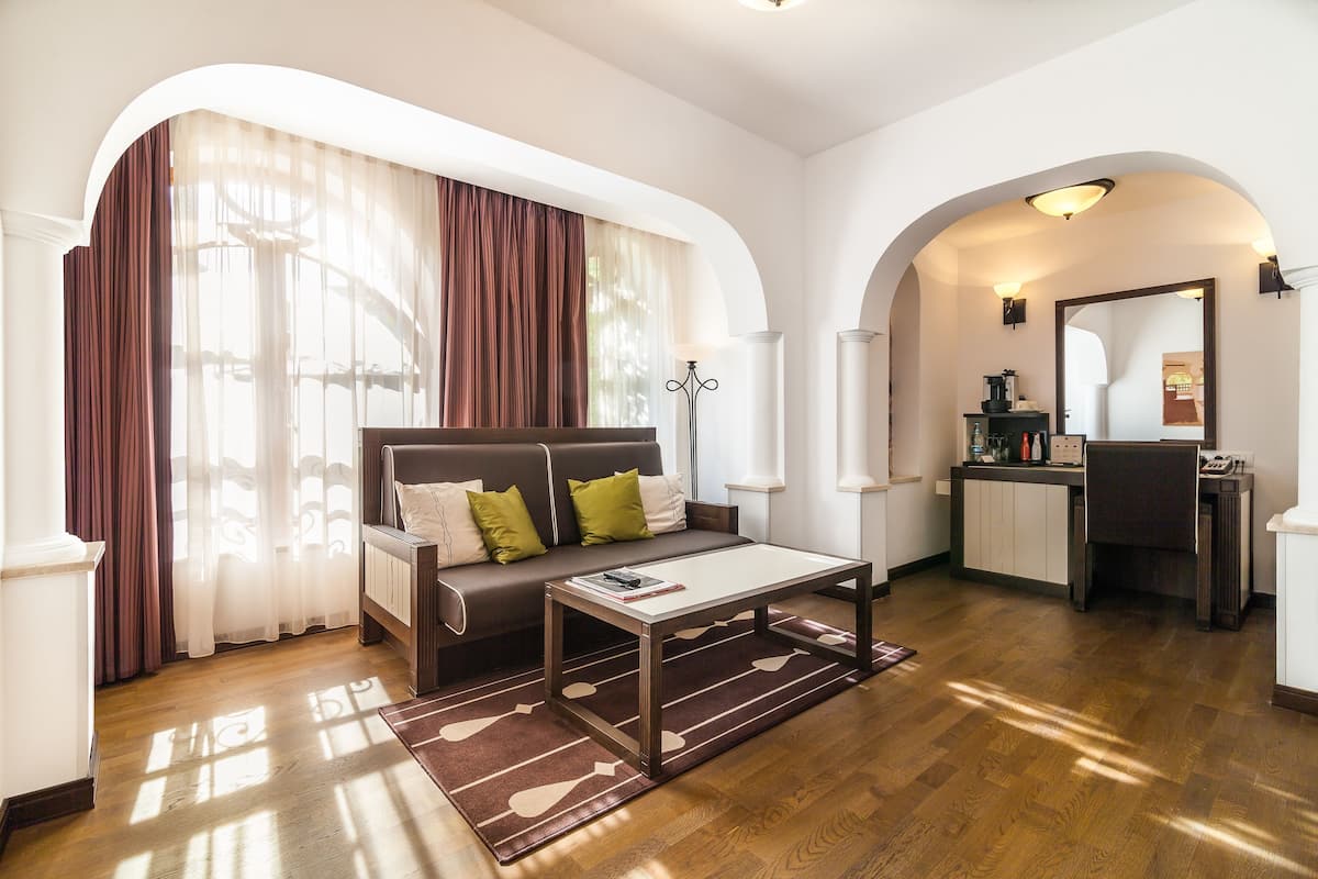 A modern living room with a sofa, coffee table, and a kitchen area visible through an archway.