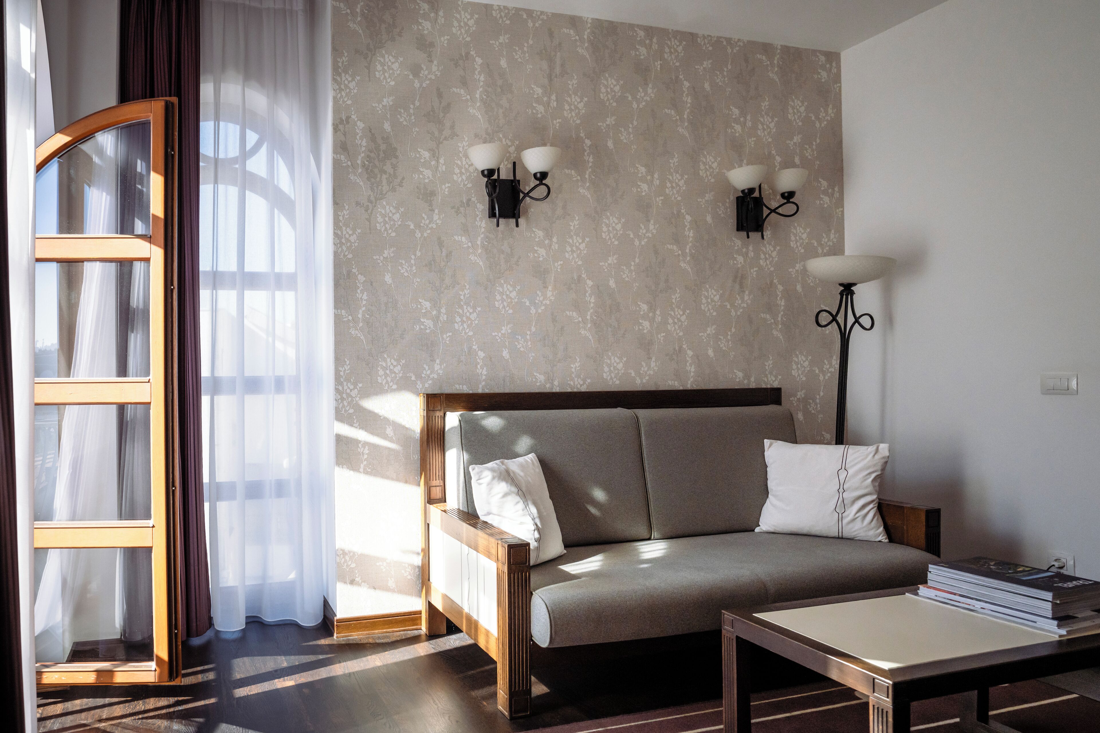 A room with a sofa, a table, and two wall-mounted lamps.