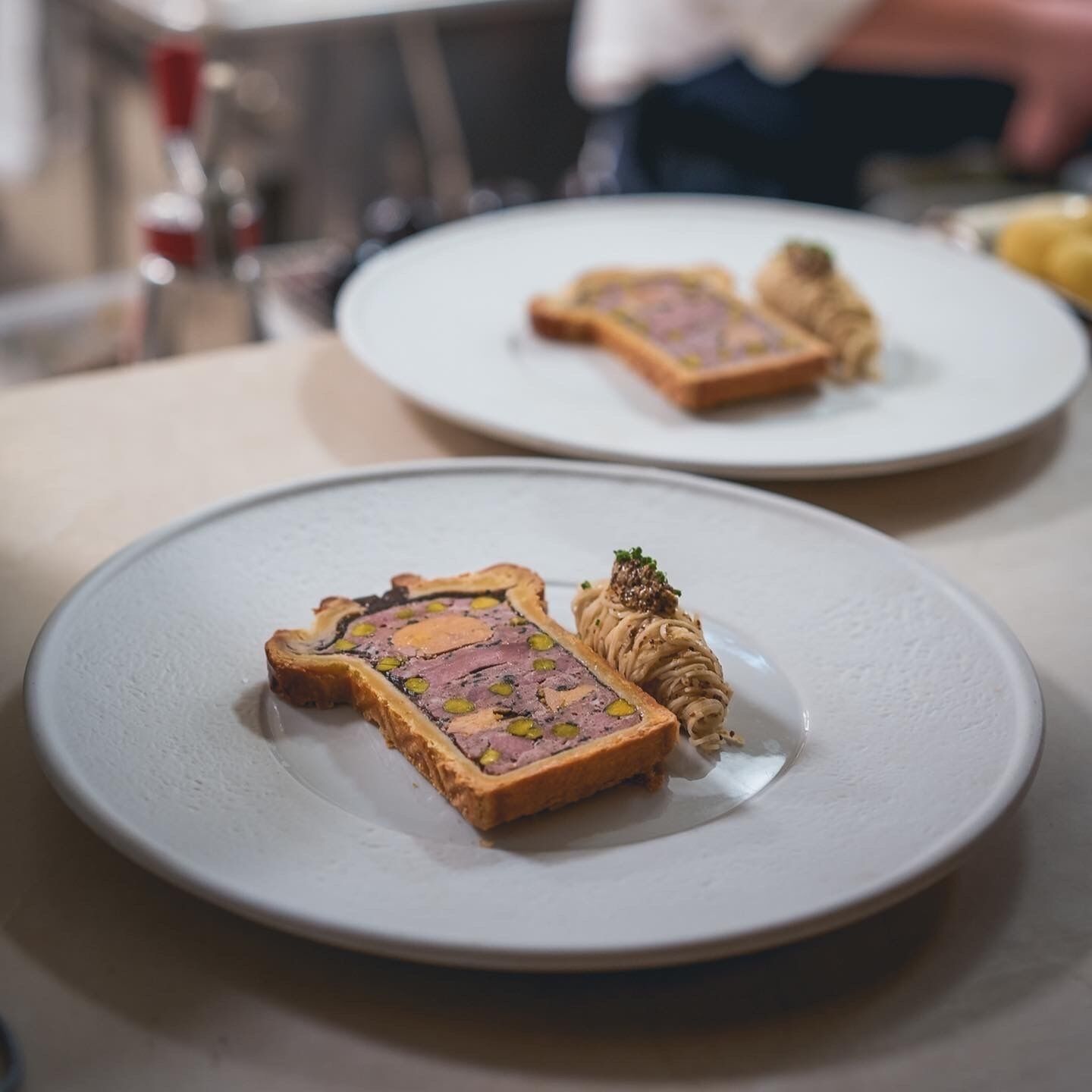 A table with two plates of food, one with a pastry and another with a rolled item and a small garnish.