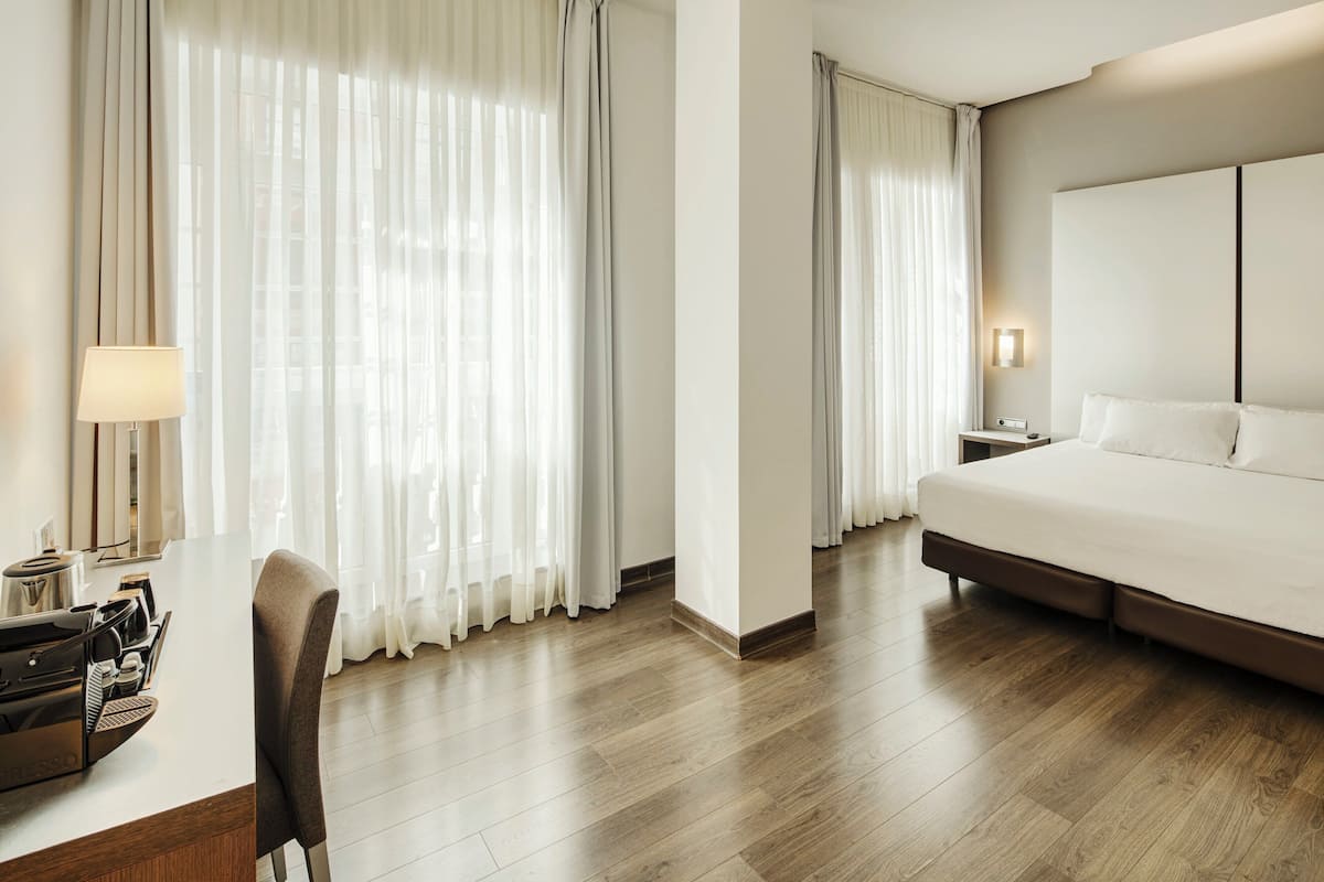 Ein Hotelzimmer mit einem Bett, einem Schreibtisch mit Lampe und einem Stuhl.