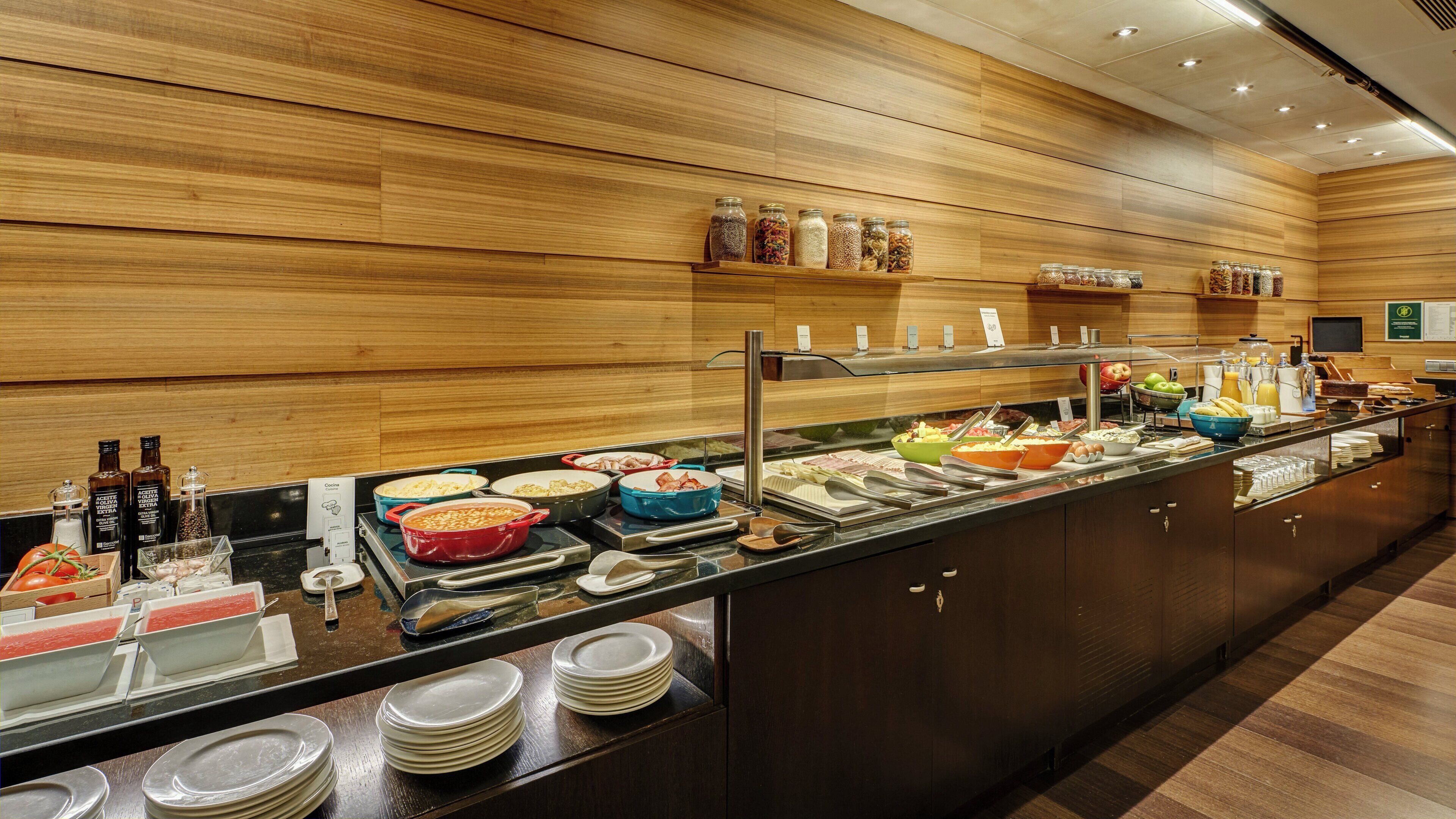 A buffet with various food items and condiments, wooden wall paneling, and a counter with plates and utensils.