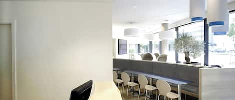A modern interior with a long counter, seating area, and large windows.