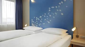 Una habitación de hotel con una cama grande, una mesita de noche con lámpara y una pared con un diseño de burbujas.