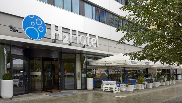 Ein modernes Hotel mit auffälligem Schild, Sitzbereich im Freien und Pflanzgefäßen.