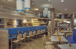 Café con menú de desayuno, asientos azules y una variedad de alimentos a la vista.